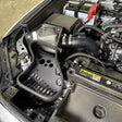 The image shows the black complete intake system installed under the hood of a vehicle, consisting of a airbox, intake tube and the area around the MAF sensor.